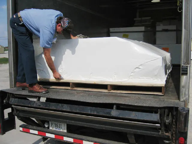 a delivery person about to cut the plastic that covers the parts of a Little Cottage Co. storage shed