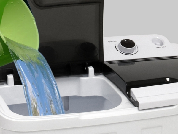 Closeup image of water being poured from a bucket into the wash tub of the Kenmore twin tub washing machine