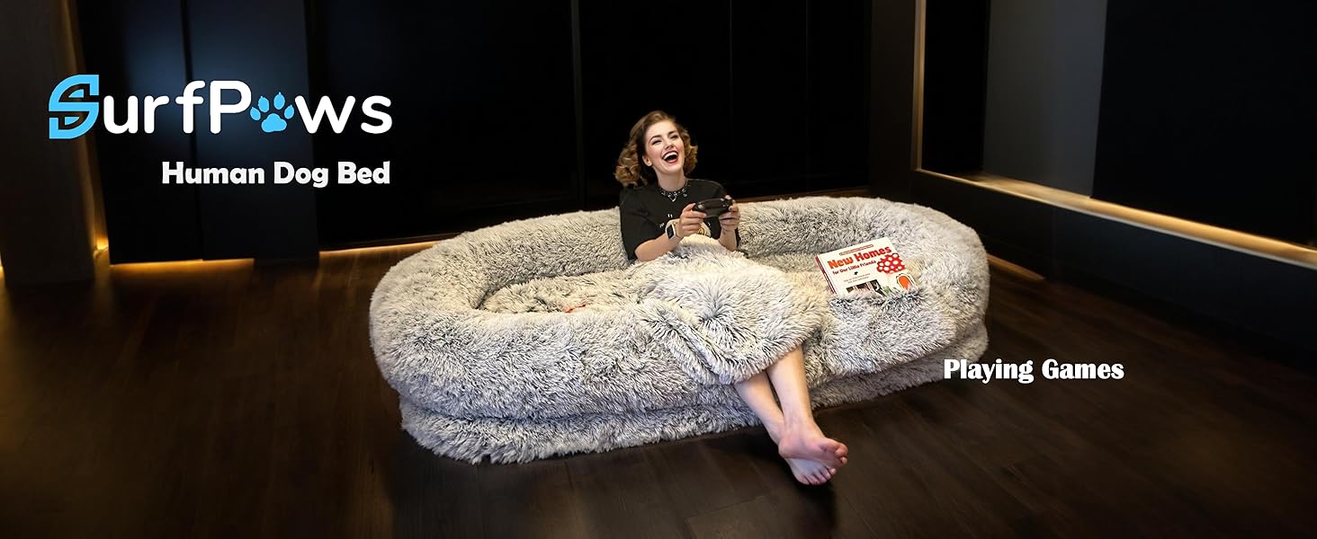 Woman playing games on the Surfpaws Human Dog Bed in a dark room, enjoying cozy moments.