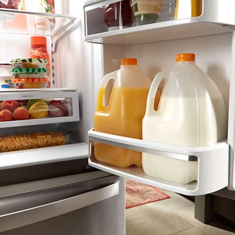Large storage bins holding a gallon of orange juice and a gallon of milk. Large storage bins holding a gallon of orange juice and a gallon of milk.