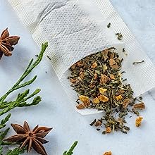 A bag of loose leaf tea on a table with greenery and star anise