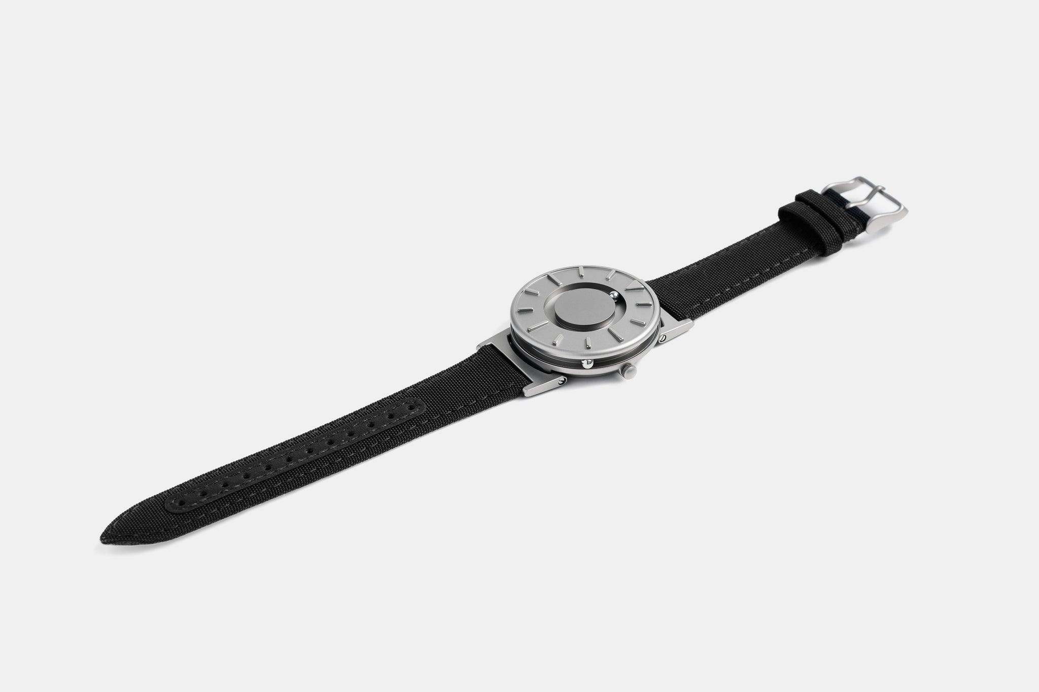 A photo of the watch lying flat on a surface. The recessed track around the outside of the watch face is shown with the hour ball bearing in the track. The raised markers are noticeable from this perspective.