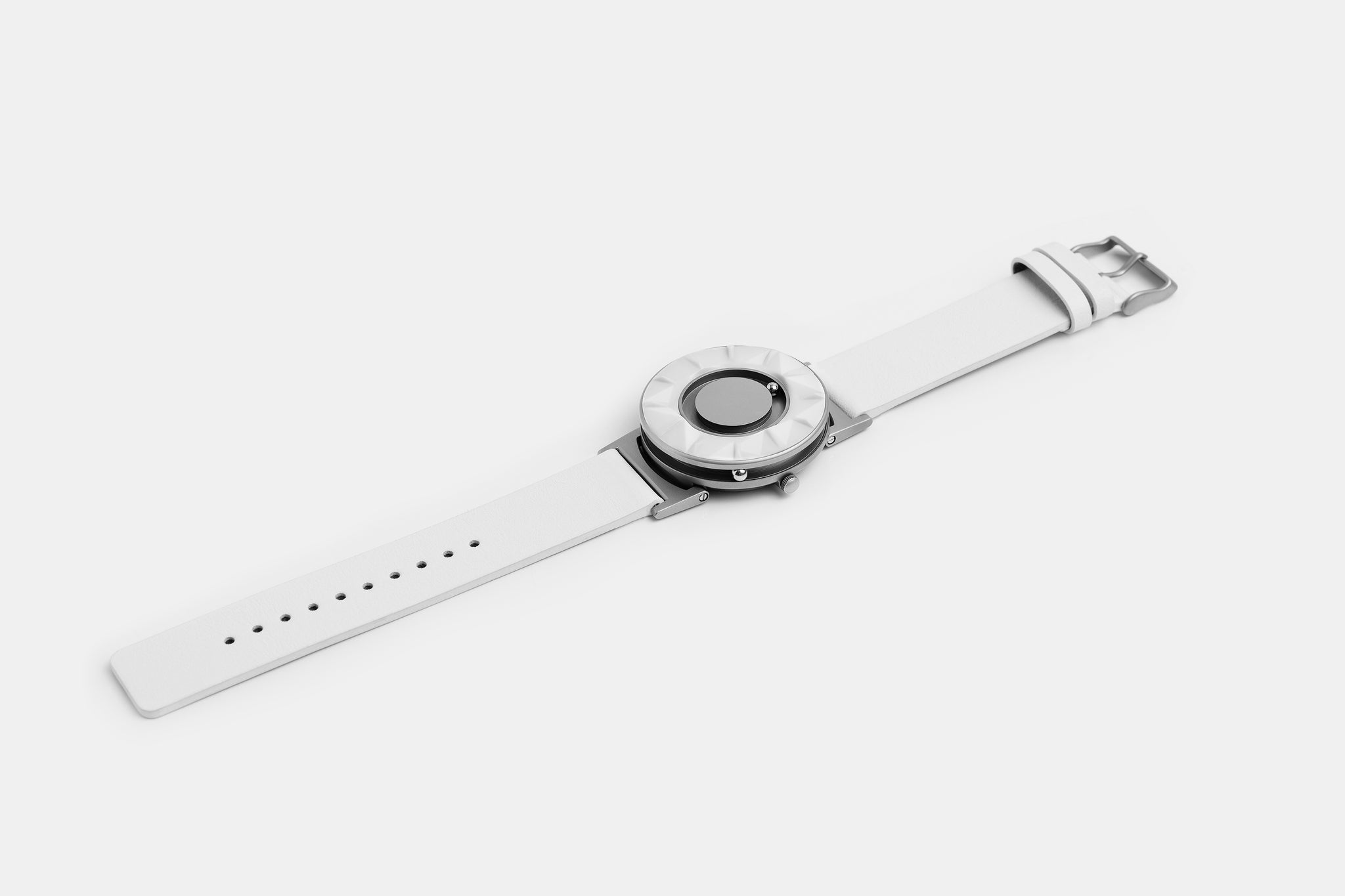 A photo of the watch lying flat on a surface. The recessed track around the outside of the watch face is shown with the hour ball bearing in the track. The raised markers are noticeable from this perspective.