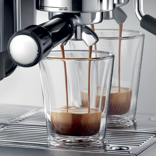 Coffee being poured into two glasses.