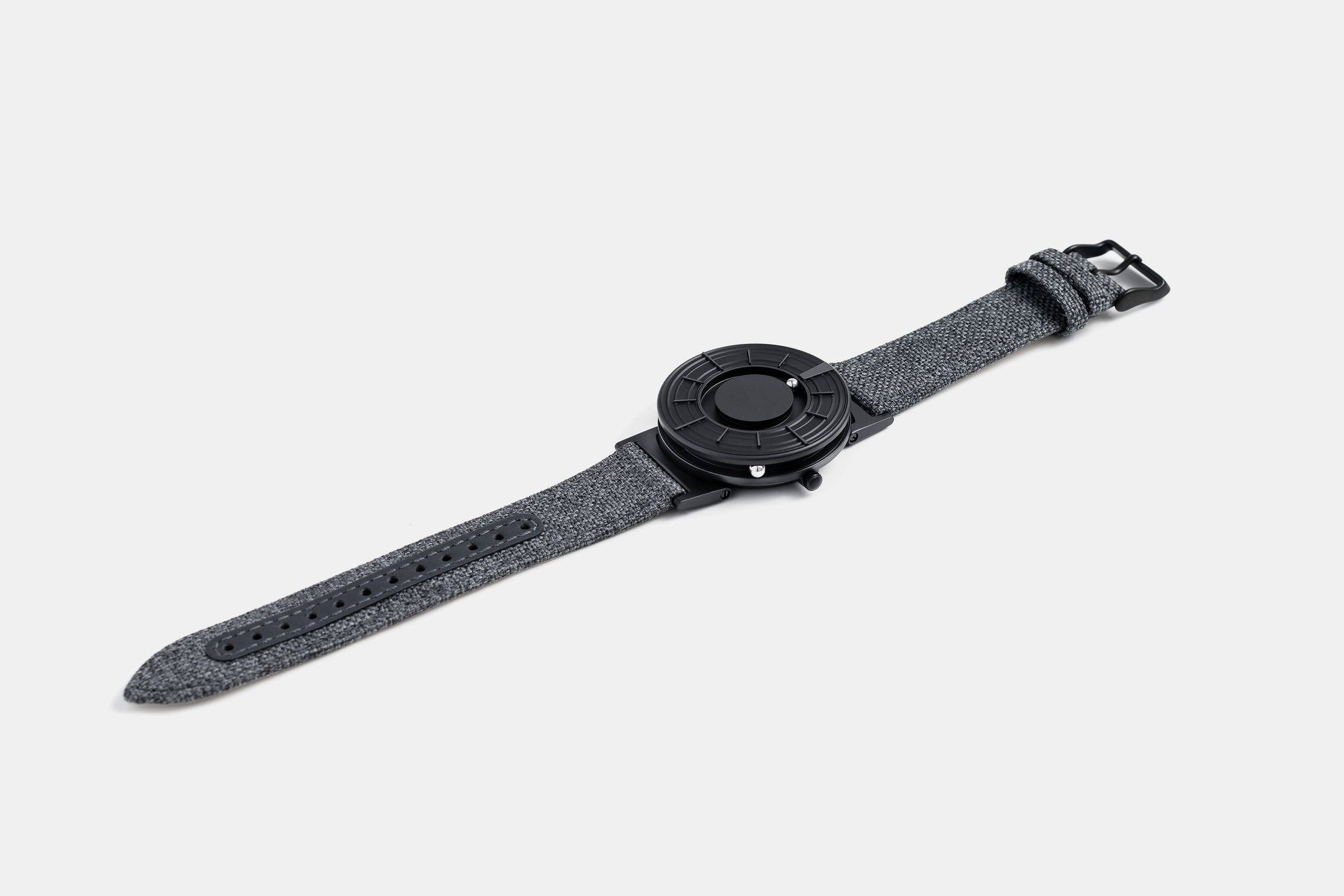 A photo of the watch lying flat on a surface. The recessed track around the outside of the watch face is shown with the hour ball bearing in the track. The raised markers are noticeable from this perspective.