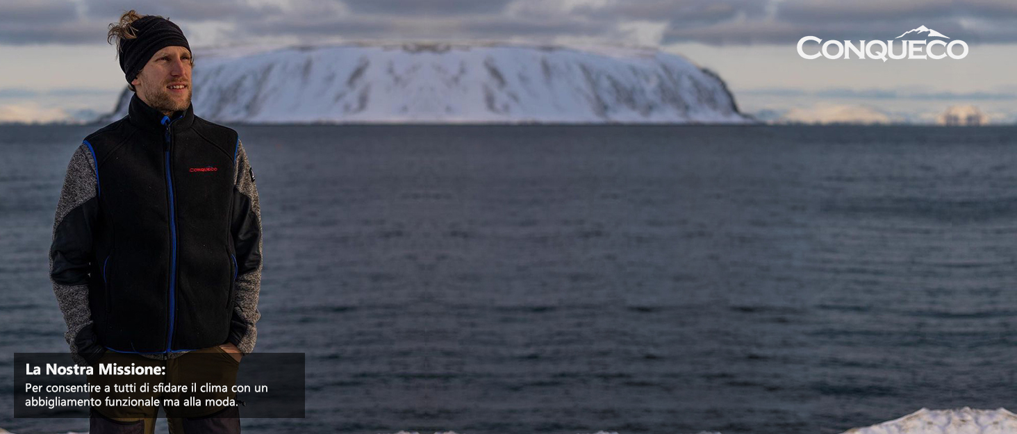 a man stands on the edge of a body of water with a mountain in the background.