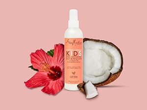 SheaMoisture Kids Detangler bottle with coconut pieces and hibiscus flower on light pink background