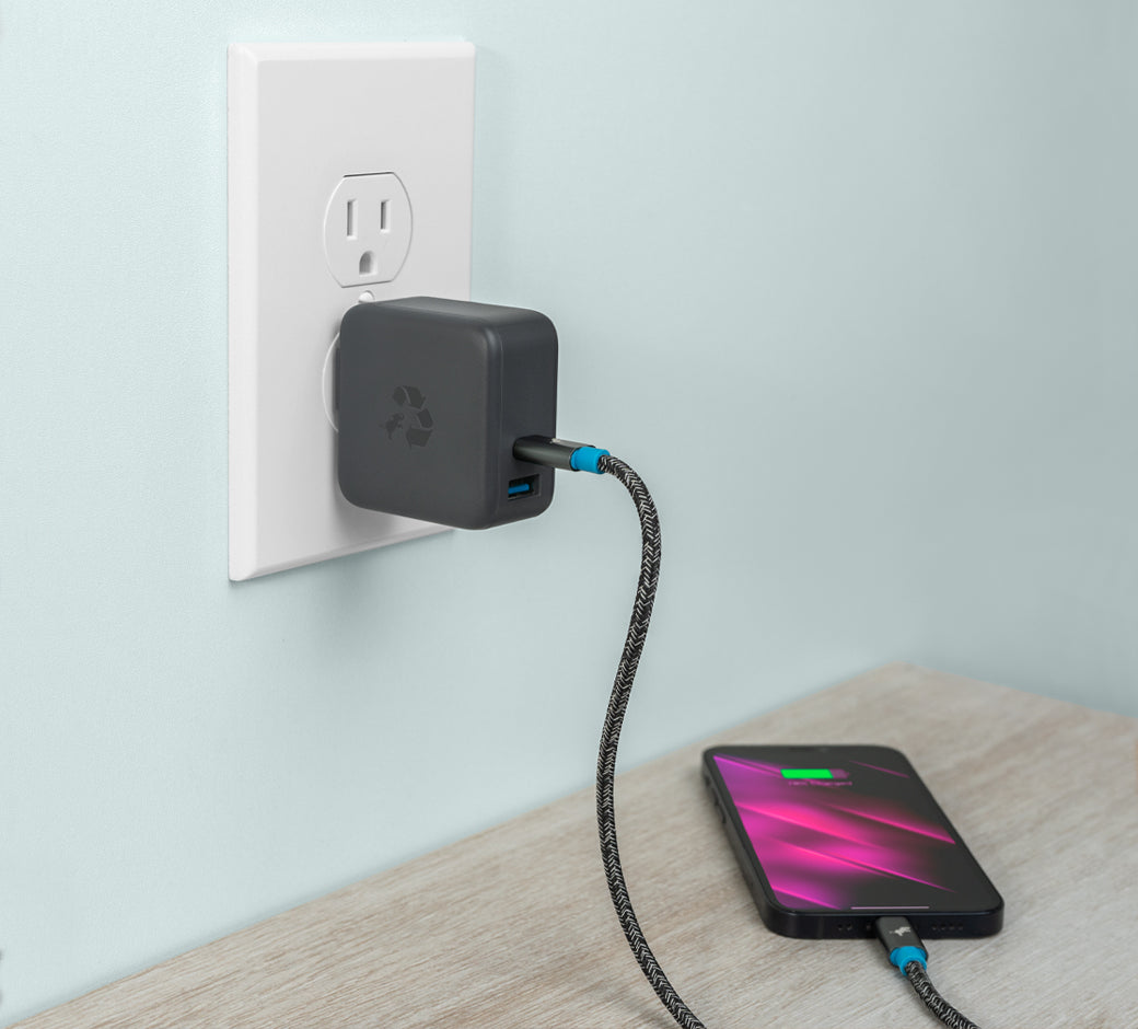 Charging device plugged into a wall outlet with a phone charging on a table nearby.