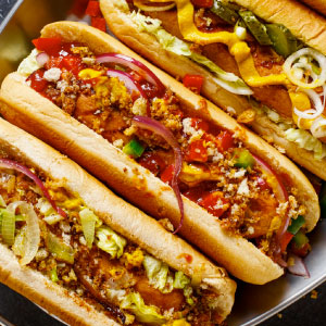 Three hot dogs on a metal tray complete with colorful condiments made in vintage toaster