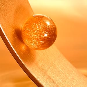 A close-up image of a translucent amber-colored pellet on a hair strand.