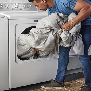 Man putting blanket in washing machine.