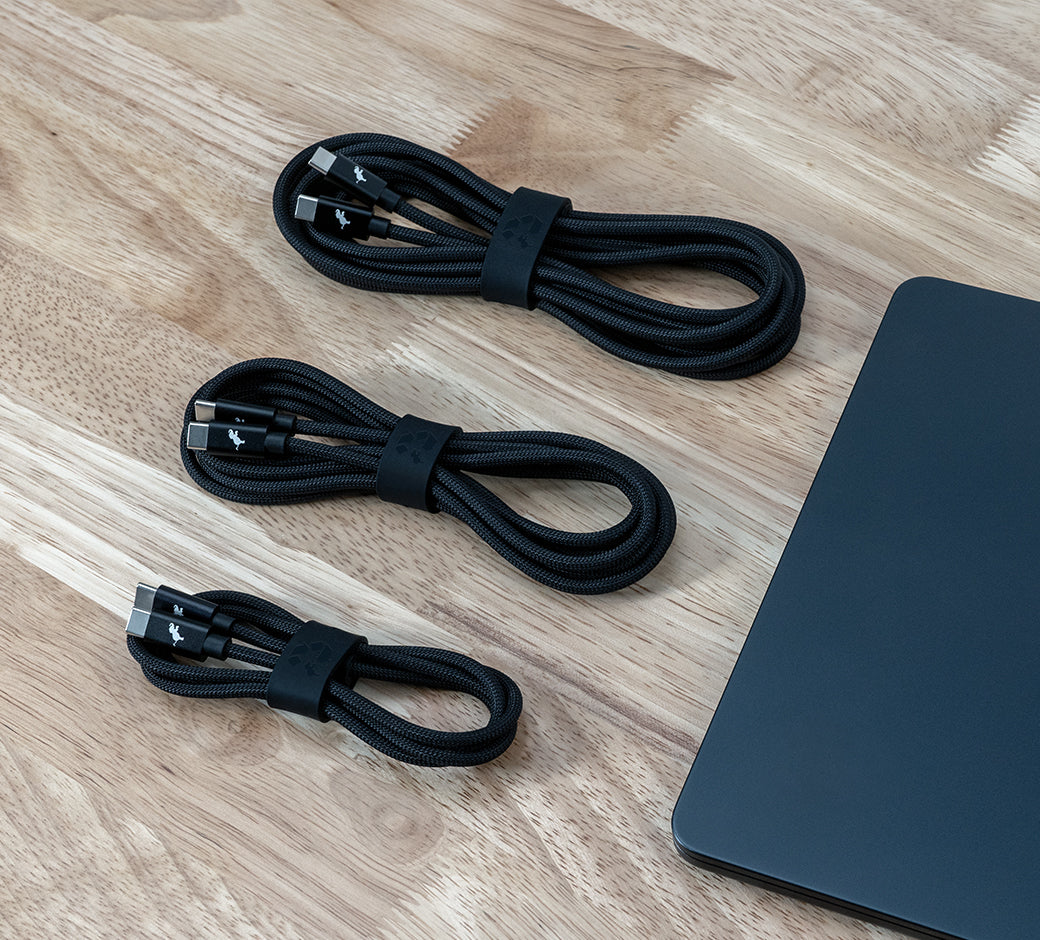 Three neatly coiled black USB-C cables with rubber straps on a wooden surface.