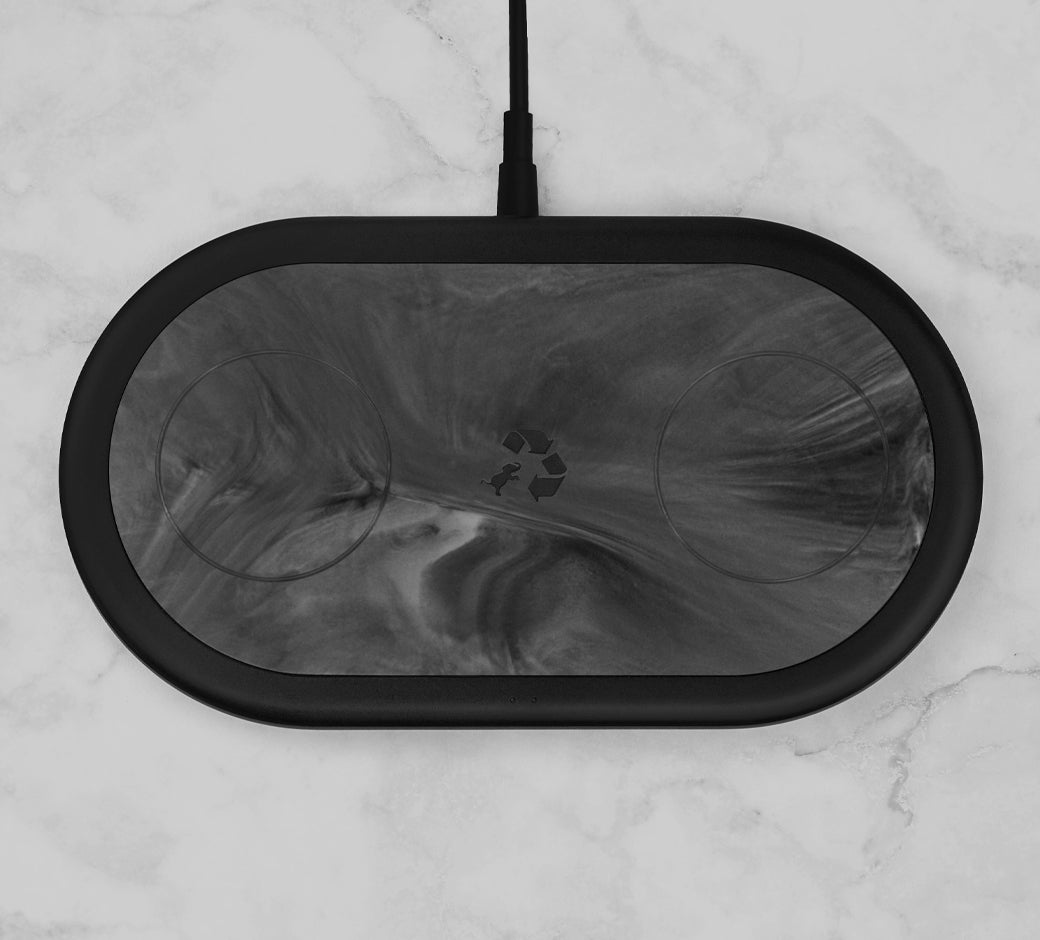 Black marbled charging pad with a recycling symbol on a marble surface.