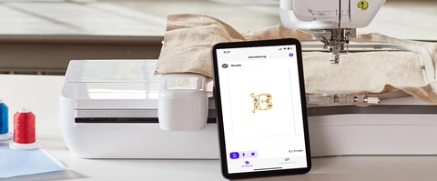 Machine on table with tablet leaning on it, featuring My Stitch Monitor app