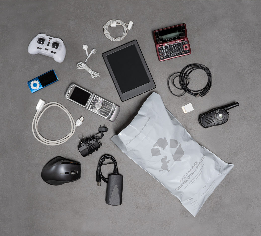 Assorted tech gadgets laid out around a recycling bag for electronic waste.