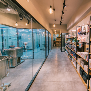 Commercial retail space with glass partition walls, track lighting, and shelving units along the wall in a corridor setting.