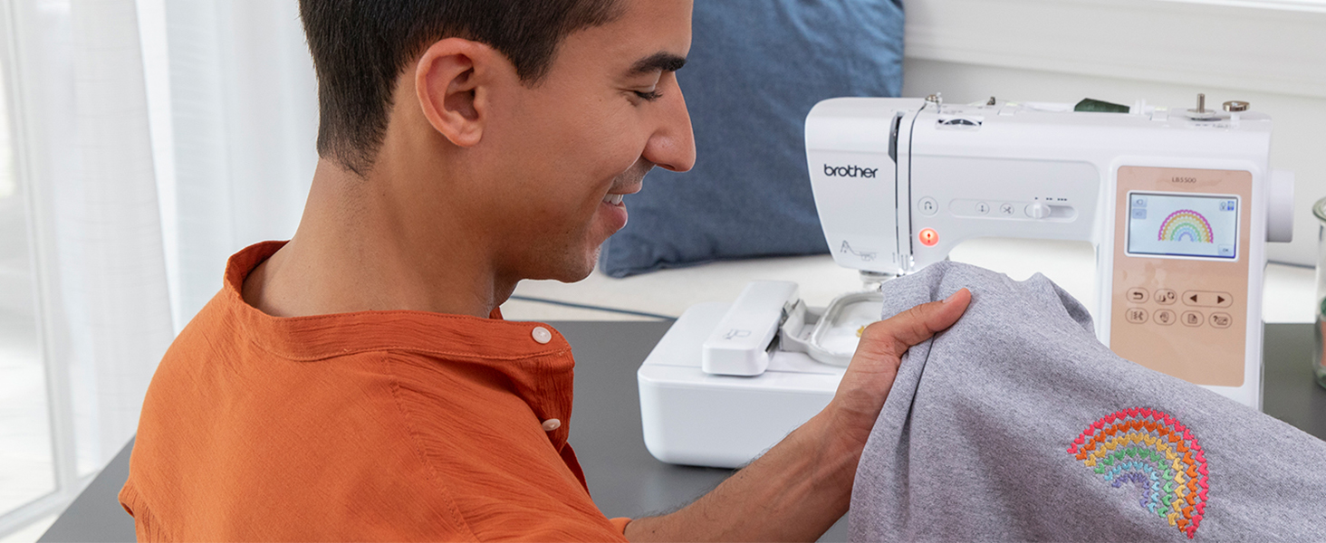 Man looking at multi-color heart rainbow design embroidered on grey sweatshirt with LB5500