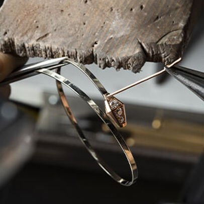 Making of the Serpenti Viper rose gold bracelet with diamonds on the head, close up.