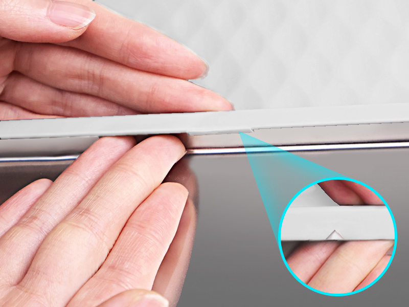 Close-up of hands applying a clear adhesive strip to an edge. Magnified inset shows detail of application.