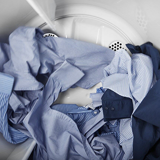 A stack of blue and white shirts being washed together in a washing machine.