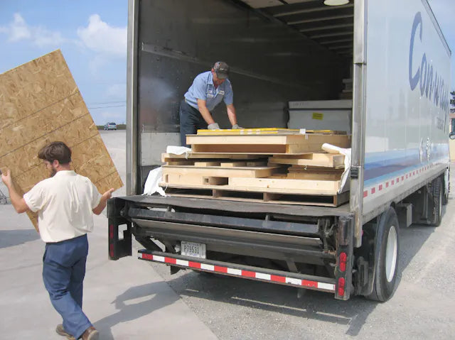A man unloading a panel piece from a delivery truck with pieces neatly stacked inside