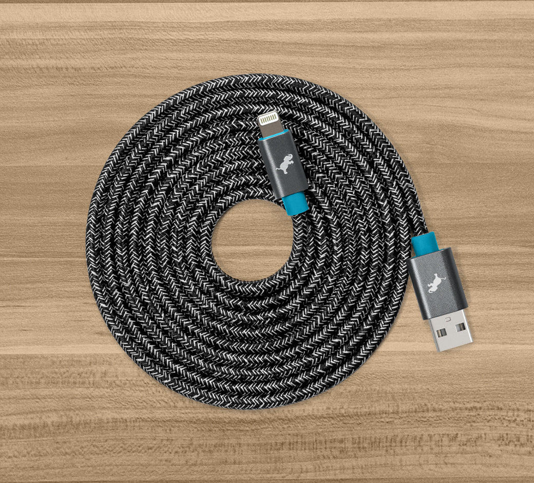 Coiled black and white braided USB cable with connectors on a wooden surface.