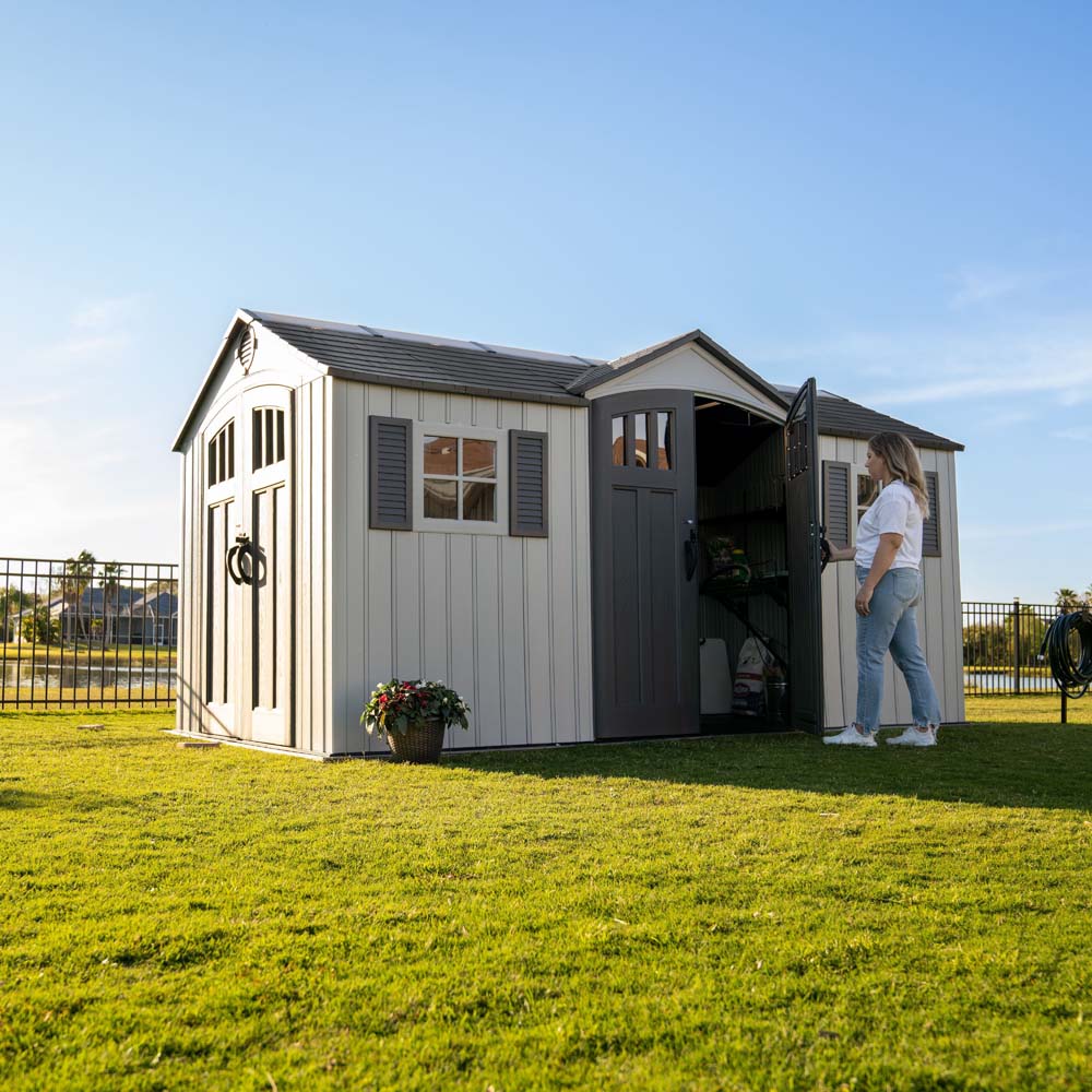 A woman opening the door of the Lifetime 15x8 Garden shed revealing plenty of storage,