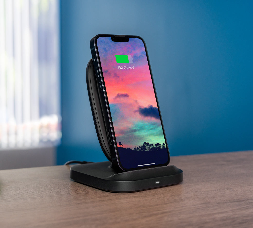 Smartphone charging upright on a black stand, displaying 78% charge with a vibrant sky background.