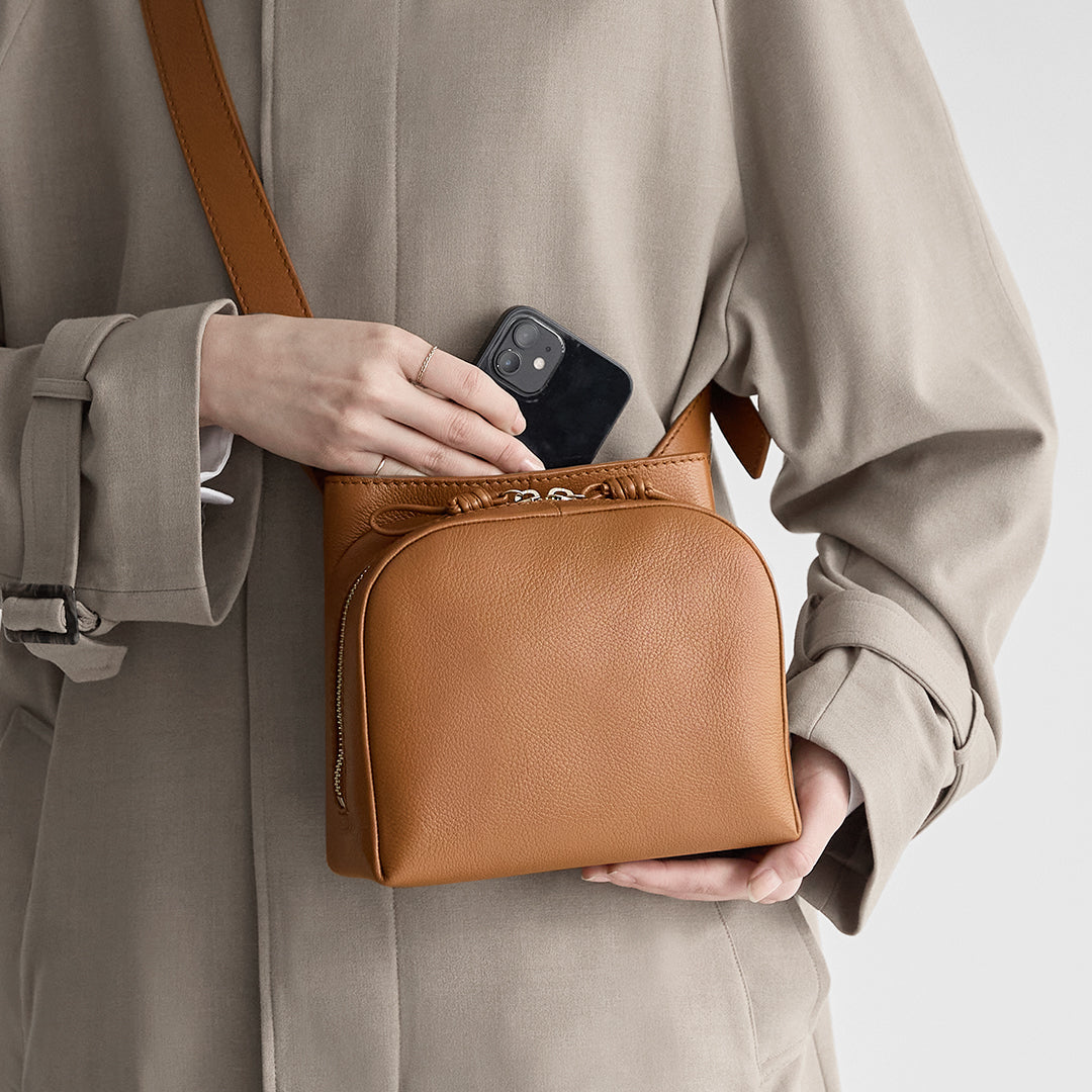 Image of a woman taking out her smartphone from the open pocket of the Sora 2 Way Shoulder M