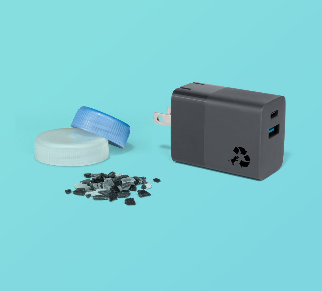 Wall charger with recycled plastic indication, next to plastic bottle caps and fragments.