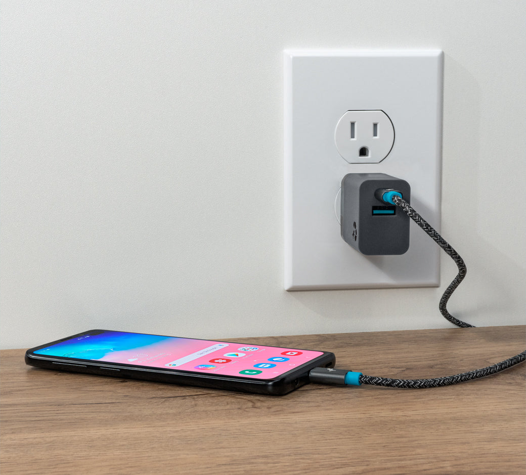 Smartphone charging with a wall charger, cable connected to a wooden table.