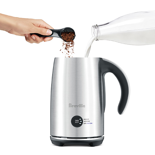 Milk frother open with milk and chocolate flakes being added.