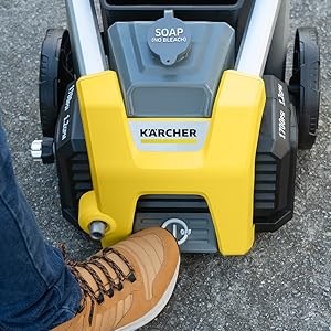 A person stepping on the on/off foot switch of the pressure washer
