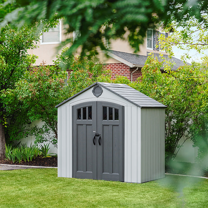 Lifetime Classic 8x5 Outdoor Shed placed in a backyard, surrounded by greenery and residential buildings.