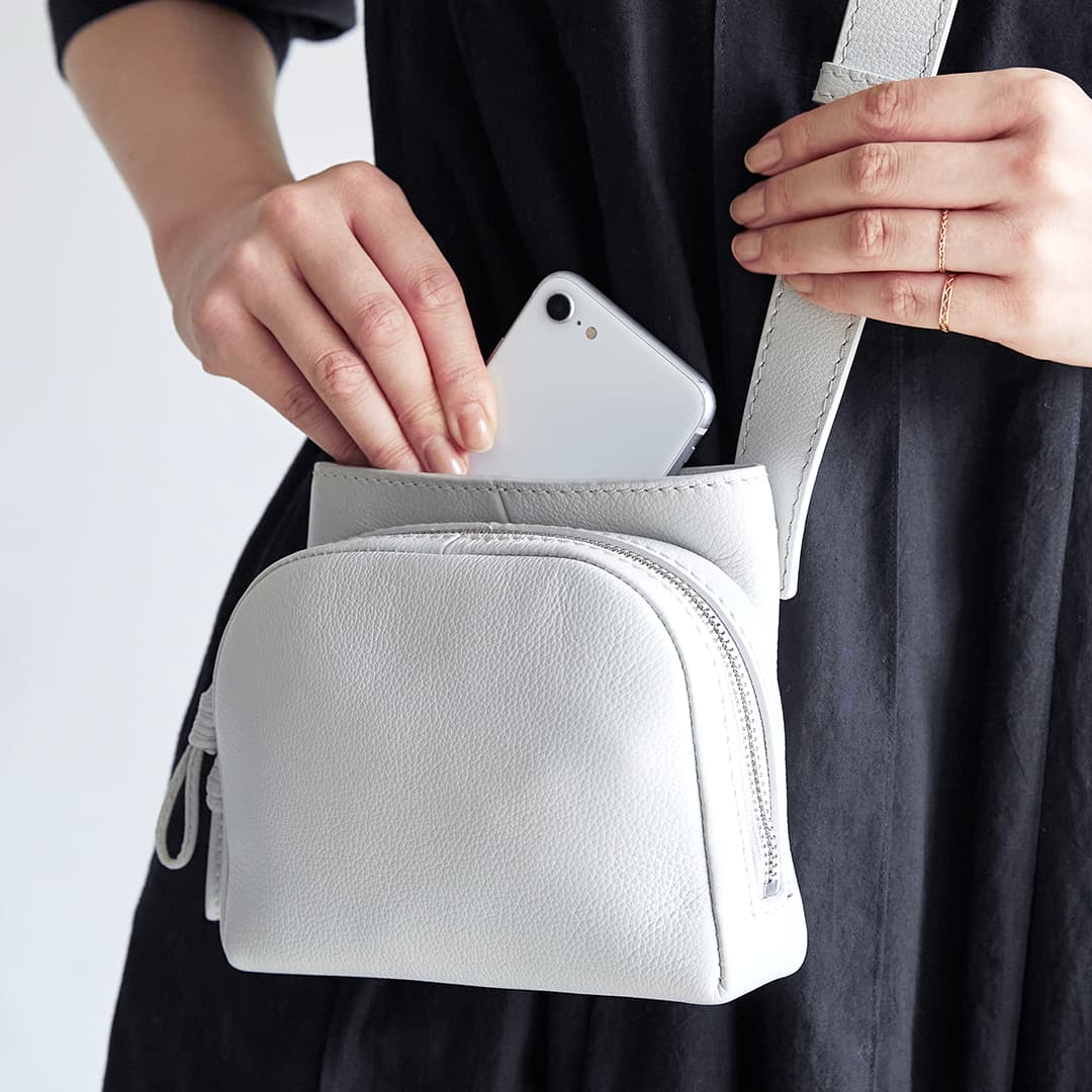 Image of a woman taking out her smartphone from the open pocket of the Sora 2-Way Shoulder S
