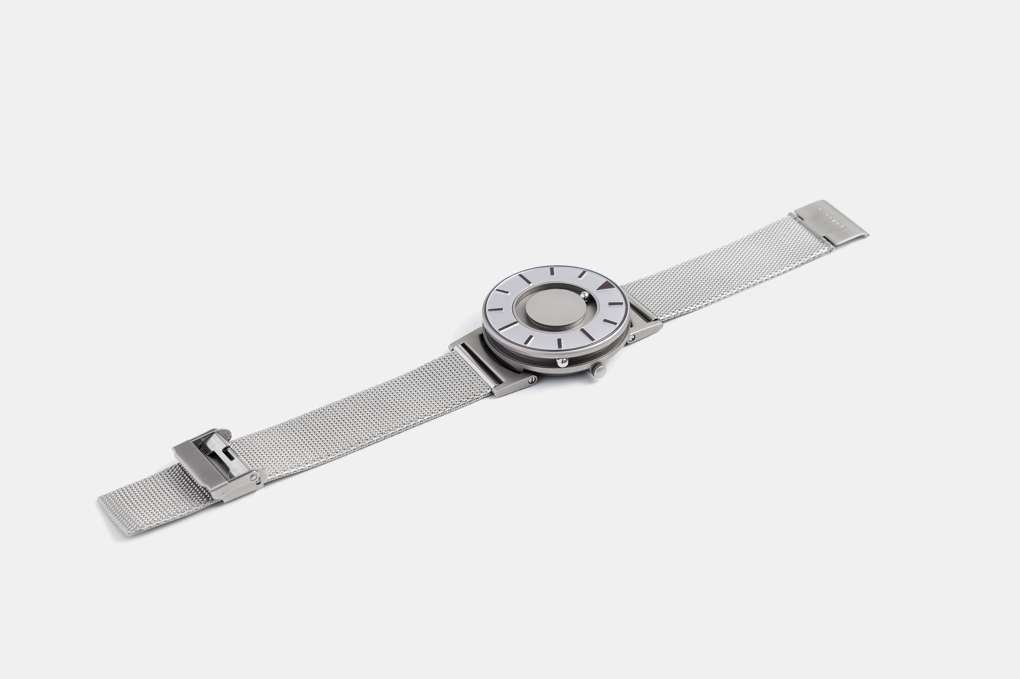 A photo of the watch lying flat on a surface. The recessed track around the outside of the watch face is shown with the hour ball bearing in the track. The raised markers are noticeable from this perspective.