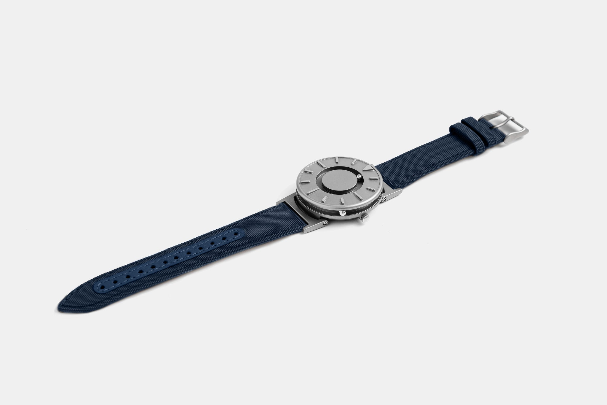 A photo of the watch lying flat on a surface. The recessed track around the outside of the watch face is shown with the hour ball bearing in the track. The raised markers are noticeable from this perspective.