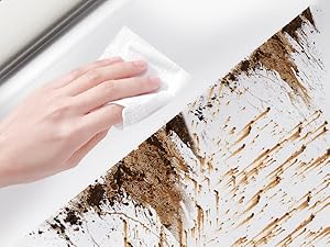 Close-up of a hand using a white cloth or wipe to clean a heavily soiled surface, likely removing mold or grime.